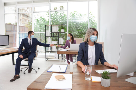 Office employees in respiratory masks at workplace - Powered by Adobe