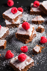 Homemade vegan chocolate brownies with nuts, lemon icing and raspberries