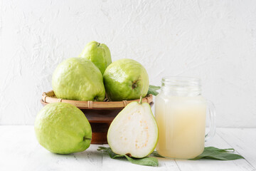 Delicious guava fruit with fresh juice set on white wooden table background.