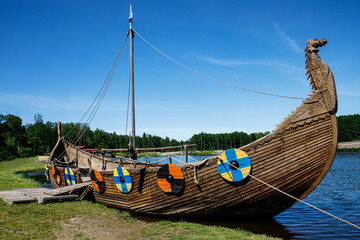 Drakkar, Viking boat moored near the grassy shore. Round shields on the housing.