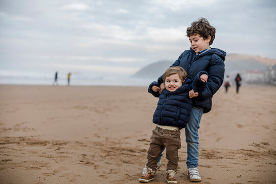 Nice image of two brothers playing on the beach and looking at the camera. Happiness concept.