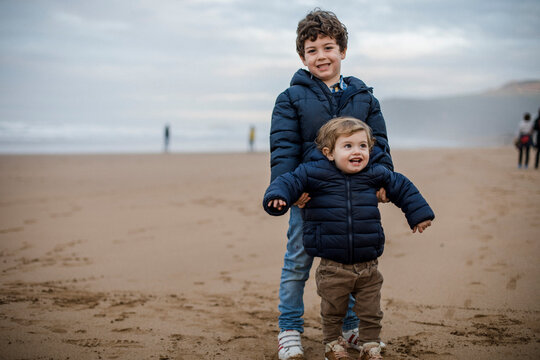 Nice image of two brothers playing on the beach and looking at the camera. Happiness concept.