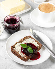 Bread with butter and blackcurrant jam. Rye bread sandwich with sunflower seeds with butter and jam. Breakfast	