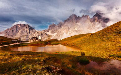 Wonderful Alpine Highlands in Sunny Day. Amazing nature landscape of Dolomites Alps. Dramatic scene with colorful sky. A magnificent panorama of the mountains with fresh grass on foreground.