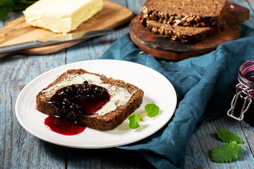 Bread with butter and blackcurrant jam. Rye bread sandwich with sunflower seeds with butter and jam. Breakfast	