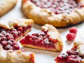 Slice of perfect raspberry galette. Delicious rustic homemade tart with frozen or fresh raspberries on white marble background. Beautiful piece of galette with raspberries, copy space