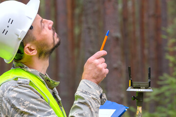 Forest worker works in the forest with measuring tools.