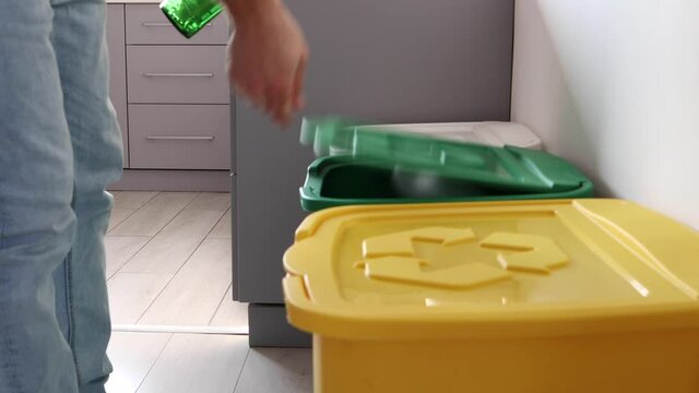 The man throws trash into the one of three dustbins