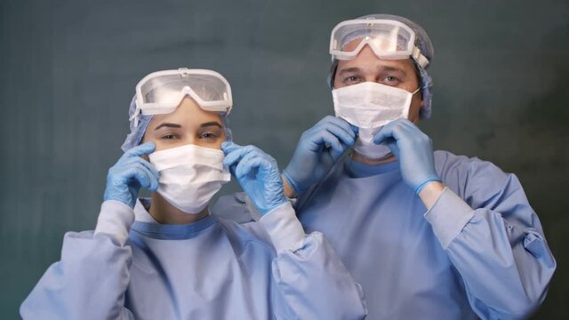 Correction of male and female doctor in masks and glasses looking at the camera.Male And Famele Doctor or Nurse Wearing Scrubs and Protective Mask and Goggles Banner.