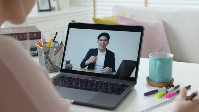 Rear view young asian woman listen watch digital class e-learning online for employee reskill upskill on notebook computer at home office workplace. Business school lesson education for adult people.