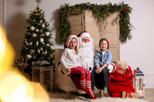 Santa Claus with little children in photo zone decorated for Christmas