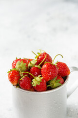 Strawberries in a metal mug on a light gray background	