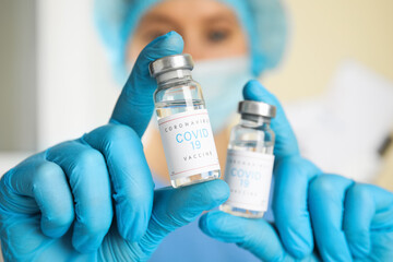 Obraz premium Doctor holding vials with vaccine against Covid-19 indoors, closeup
