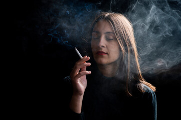 Fototapeta premium Young woman smoking cigarette on black background
