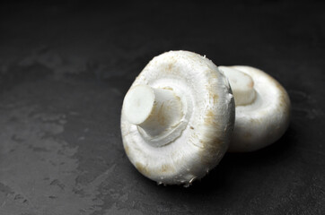 Raw champignon mushrooms on black background. Vegan food concept.