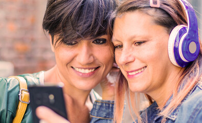 couple of friends look at cellphone together smiling