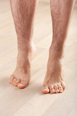 man doing flatfoot correction gymnastic exercise standing on toes at home