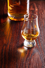 Bottle and glass of whisky spirit brandy on dark brown background