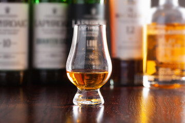 Bottles and glass of whisky spirit brandy on dark brown background