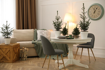 Beautiful room interior with dining table and potted fir trees. Christmas decor