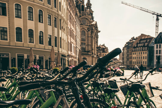 Travel concept photo of rental bikes at Neustadt Square in Dresden. Closeup sharp details of bike and atmospheric bokeh of classic 18th century architecture. 