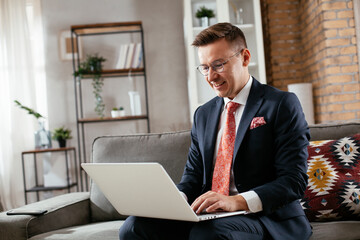 Young businessman working with laptop at office. Businessman sitting on sofa having video call