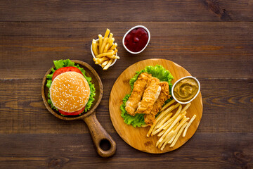 Top view of delicious burgers on on wooden board. Fried potatoes and chicken