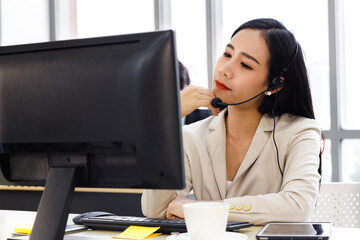 Asian call center agent working on computer at office.