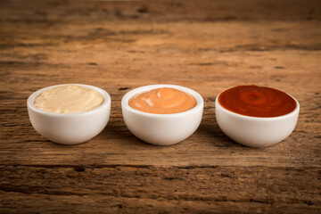 Ketchup, mayonnaise and rose sauce on rustic wooden background