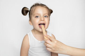 Close up of pretty little child girl with open mouth during a medical examination. Hand of the...