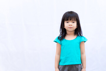 Asian child stands upright looking at the camera. A white wall as a background. Copy space. Kids wear green clothes. Smile a little.