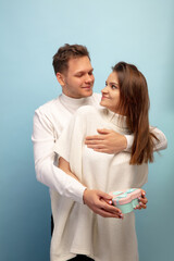 Pastel. Beautiful couple in love on blue studio background. Saint Valentine's Day, love, relationship and human emotions concept. Copyspace. Young man and woman look happy together.