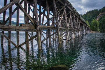 Weathered trestle bridge over a scenic Vancouver Island lake.