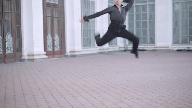 Wide shot of skilled professional ballet dancer spinning and jumping in urban city. Portrait of confident talented Caucasian handsome man dancing outdoors. Art performance and choreography.