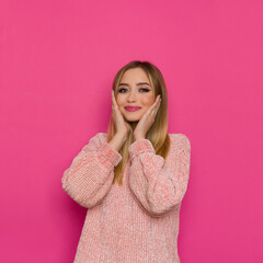 Happy Young Woman In Pink Sweater Is Holding Head In Hands.