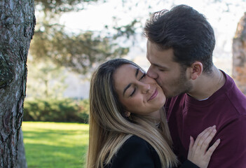 Fototapeta premium Lovers Kissing Outdoors In The Park. Happy Lovers By A Park. In Love
