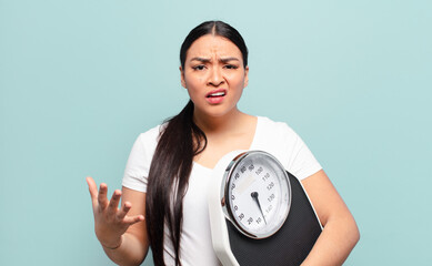 hispanic woman looking angry, annoyed and frustrated screaming wtf or what’s wrong with you