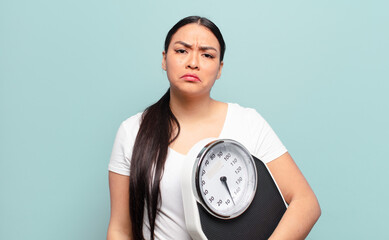 hispanic woman feeling sad and whiney with an unhappy look, crying with a negative and frustrated...