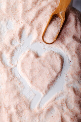 Pink Himalayan salt powder with a heart-shaped mark on it. Food background.