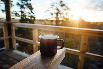 Sunny early morning. Metal mug with a hot drink, steam rises from the mug. There is a place for text, logo