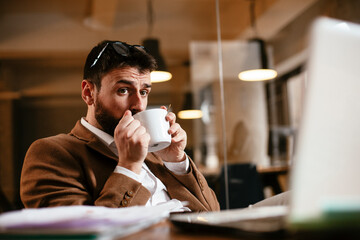 Young businessman drinking coffee in the office. Handsome man on coffee break.