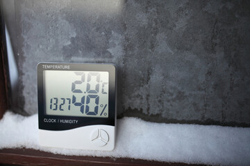 The humidity indicator is indicated on a hygrometer installed on the snow. Picture of an electronic device for testing air temperature and humidity. - obrazy, fototapety, plakaty