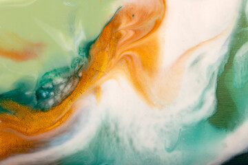 Bright flowing alcohol Ink gold colors on blue green background. Acrylic Fluid Art. Liquid marble...