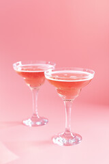 Two glasses with sparkling rose wine on pink background