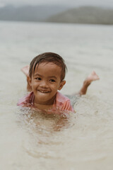 Portrait Happy Little Filipino Asian Boy Running and Playing while Smiling and Laughing on Tropical Beach at sunset. Adorable Young Kid having Fun in Summer Holiday Vacation Travel in the Philippines.