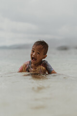 Portrait Happy Little Filipino Asian Boy Running and Playing while Smiling and Laughing on Tropical Beach at sunset. Adorable Young Kid having Fun in Summer Holiday Vacation Travel in the Philippines.