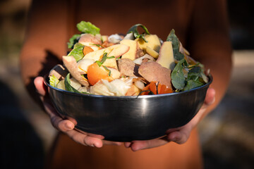 Kitchen compost. Woman hands holding. a bowl of vegetable peels to make organic compost