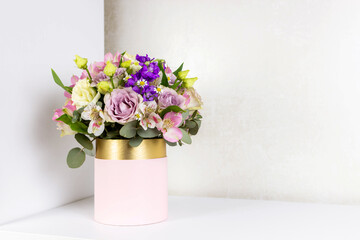 Beautiful bouquet of flowers in pink round box on a white table. Gift for holiday, birthday,...