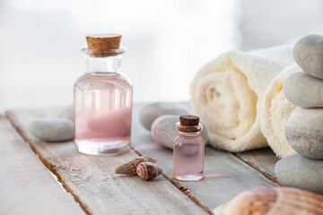 Natural organic spa products on wooden background. Essential rose oil, towel, stones. Atmosphere of relax, detention, zen. Aromatherapy. Body care, healthy lifestyle. Close up. Copy space for text.