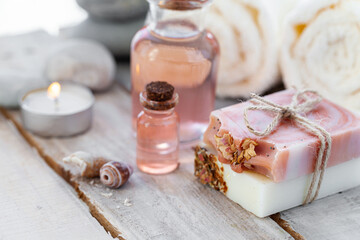 Natural organic spa products on wooden background. Essential rose oil, towel, stones. Atmosphere of relax, detention, zen. Aromatherapy. Body care, healthy lifestyle. Close up. Copy space for text.